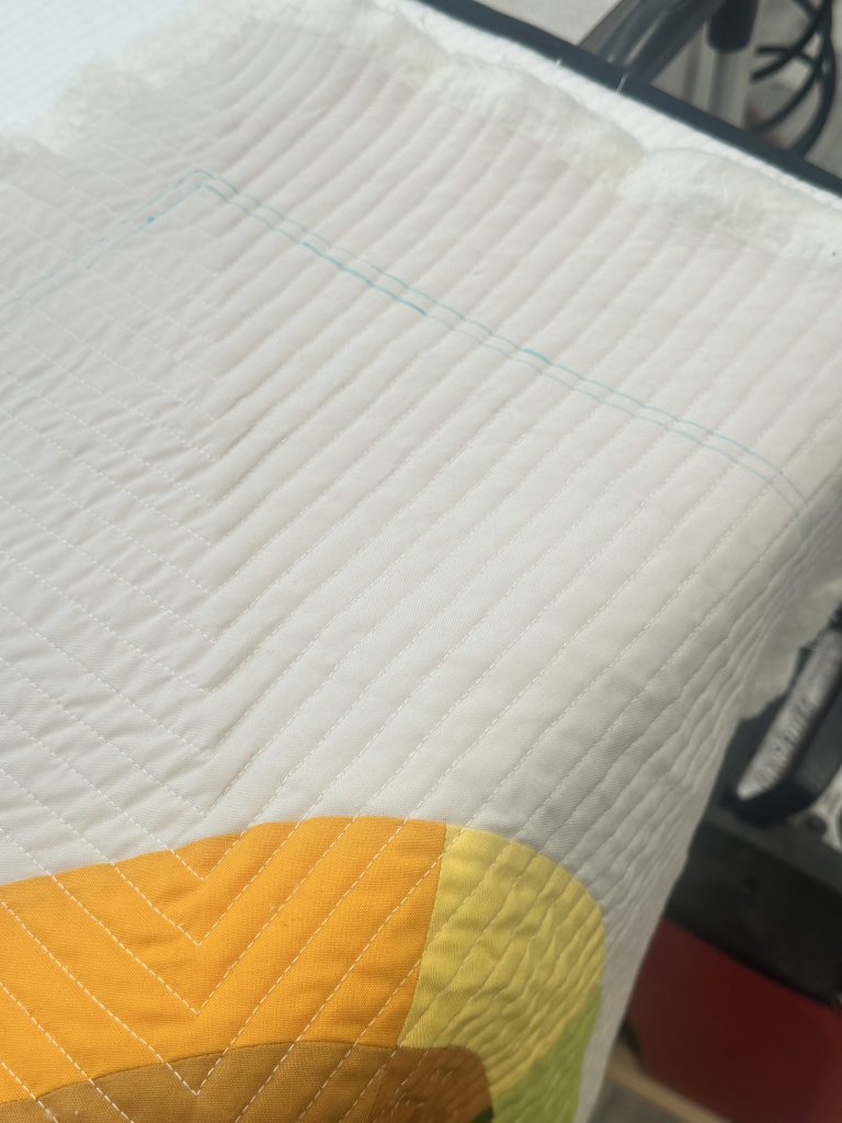 Close-up of a quilted fabric showing a textured white surface and a colorful yellow section.