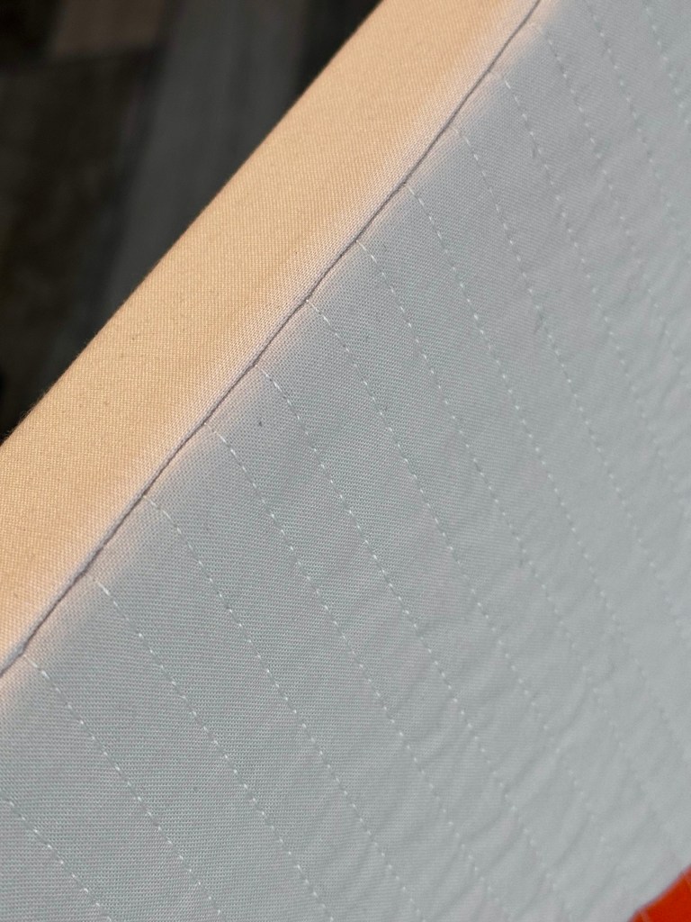 Close-up view of a quilted fabric edge featuring a visible seam and contrasting colors.